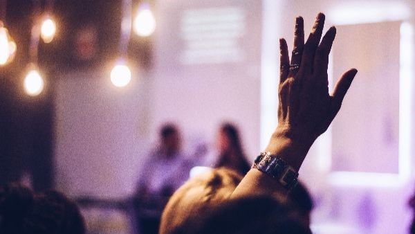 Hand raised in the audience of a public talk.
