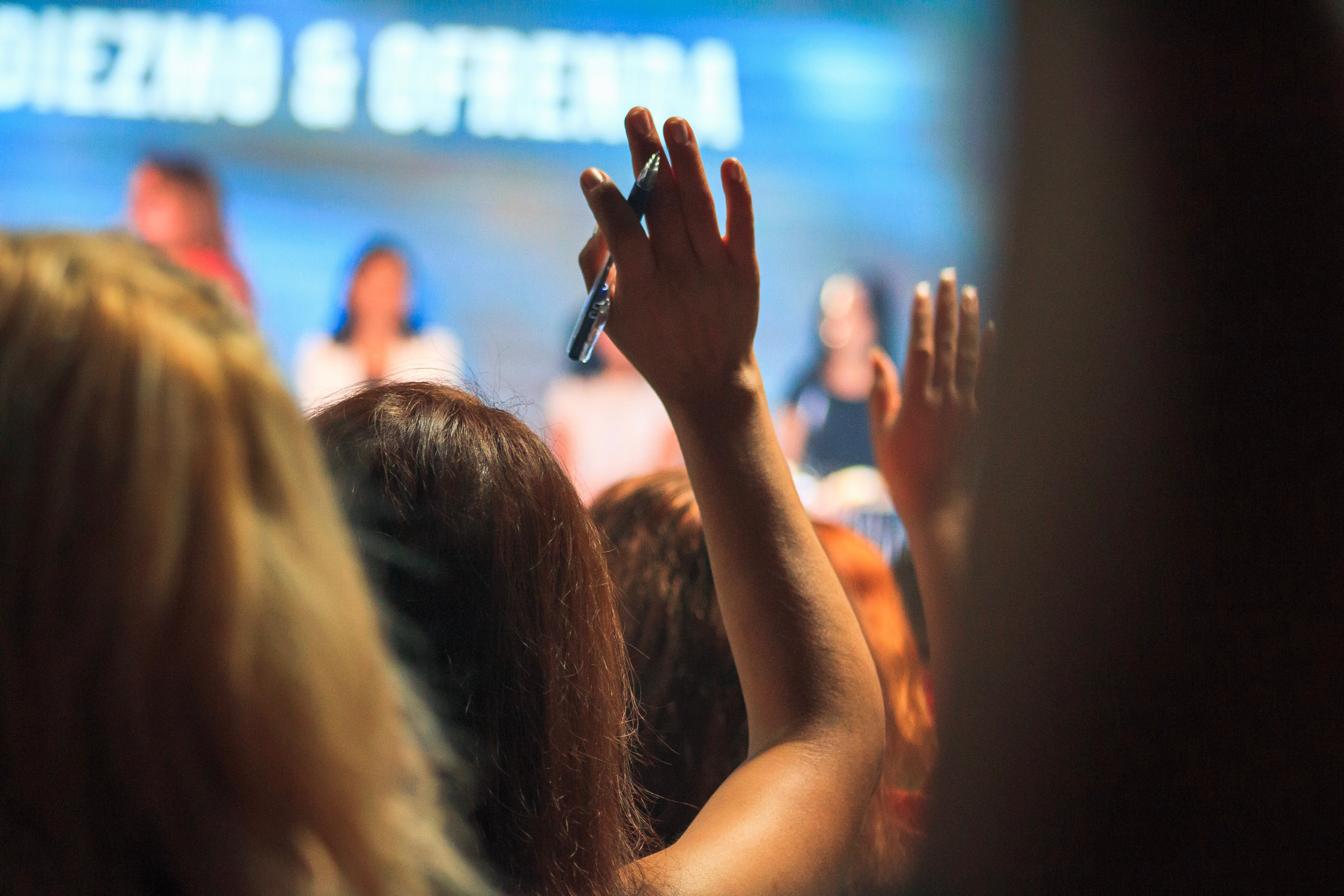 Hand raised in the audience of a lecture.