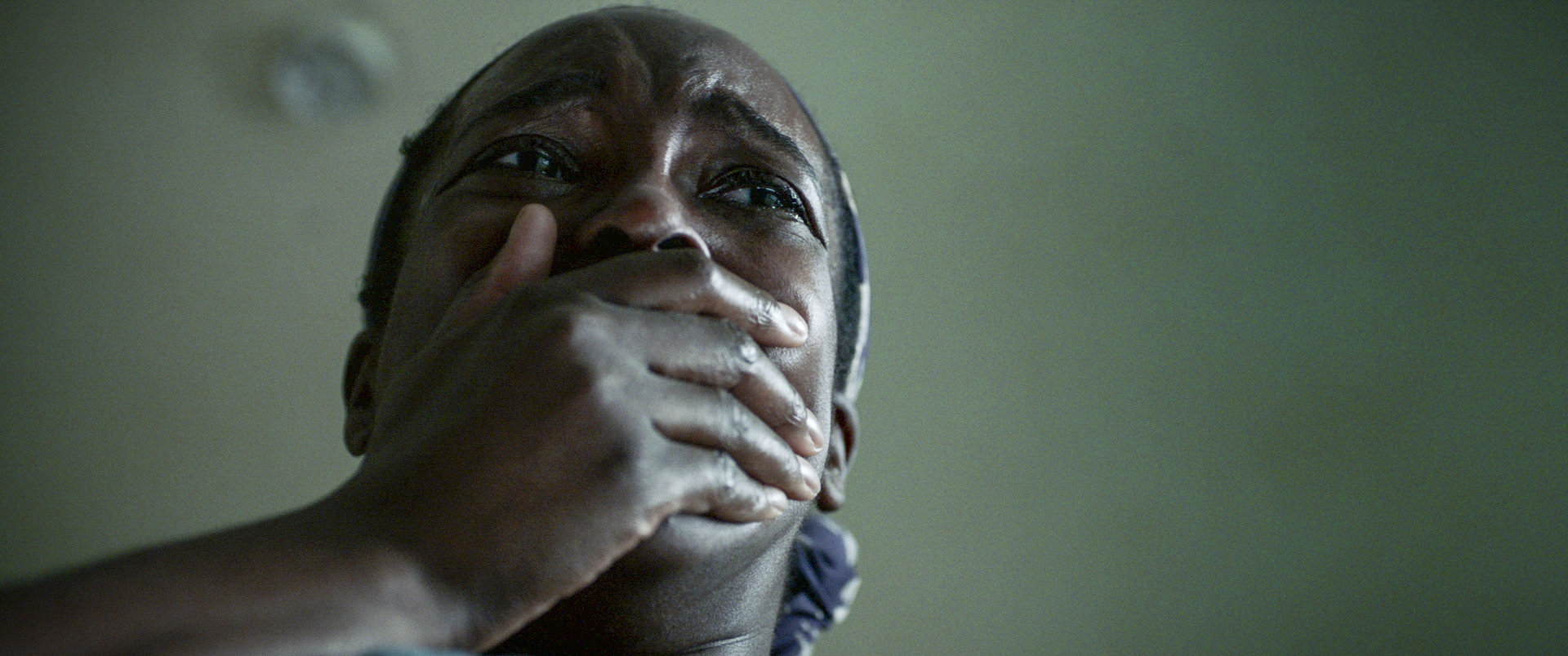 Still from 'His House' showing woman with hand over mouth