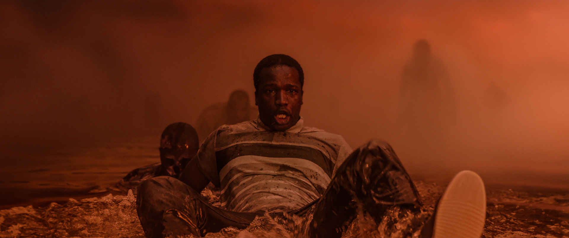Still from 'His House' showing man sitting back in water surrounded by dark figures