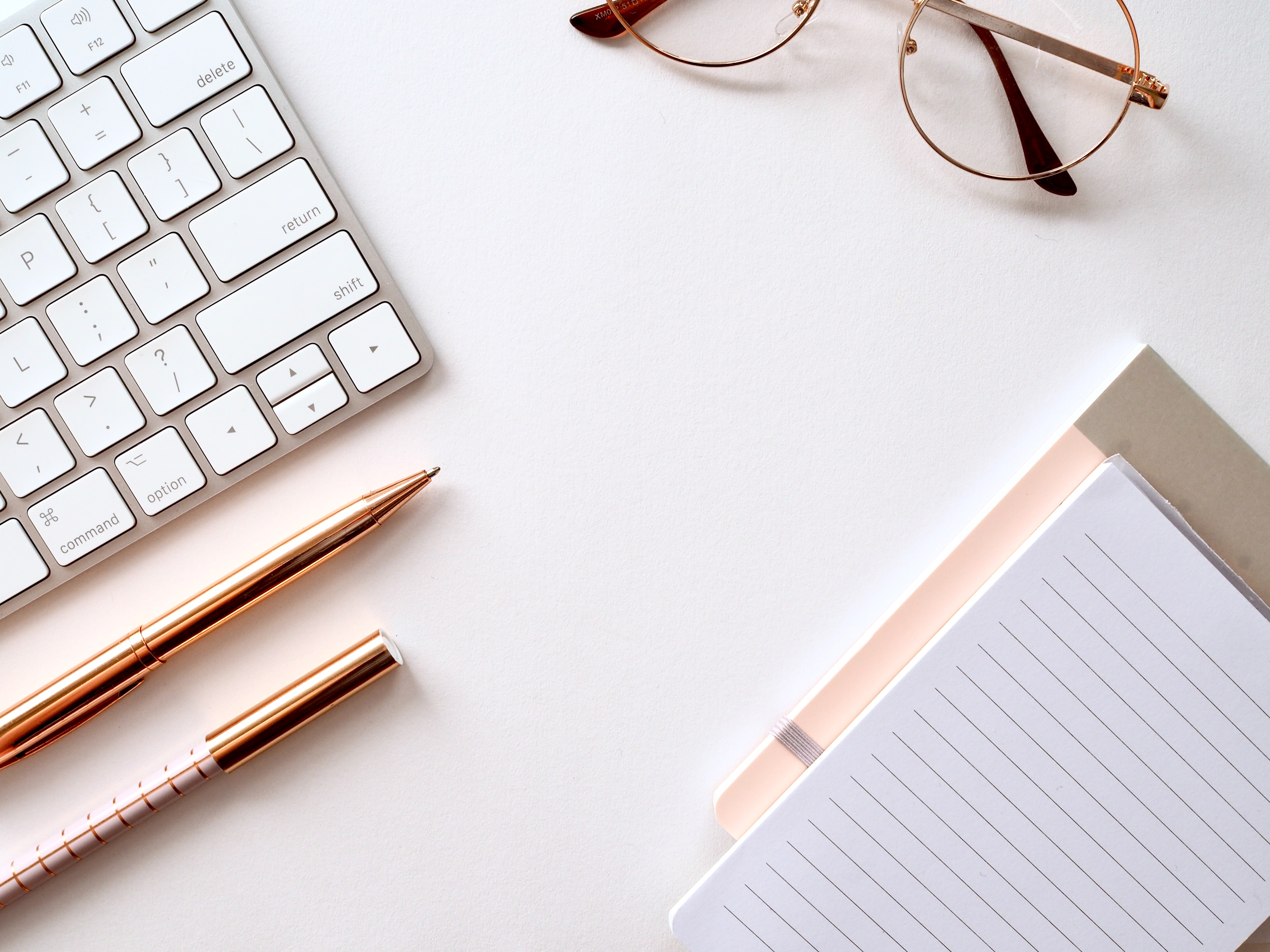 A photo of a keyboard, pen and notepad. Jess Bailey - Unsplash.
