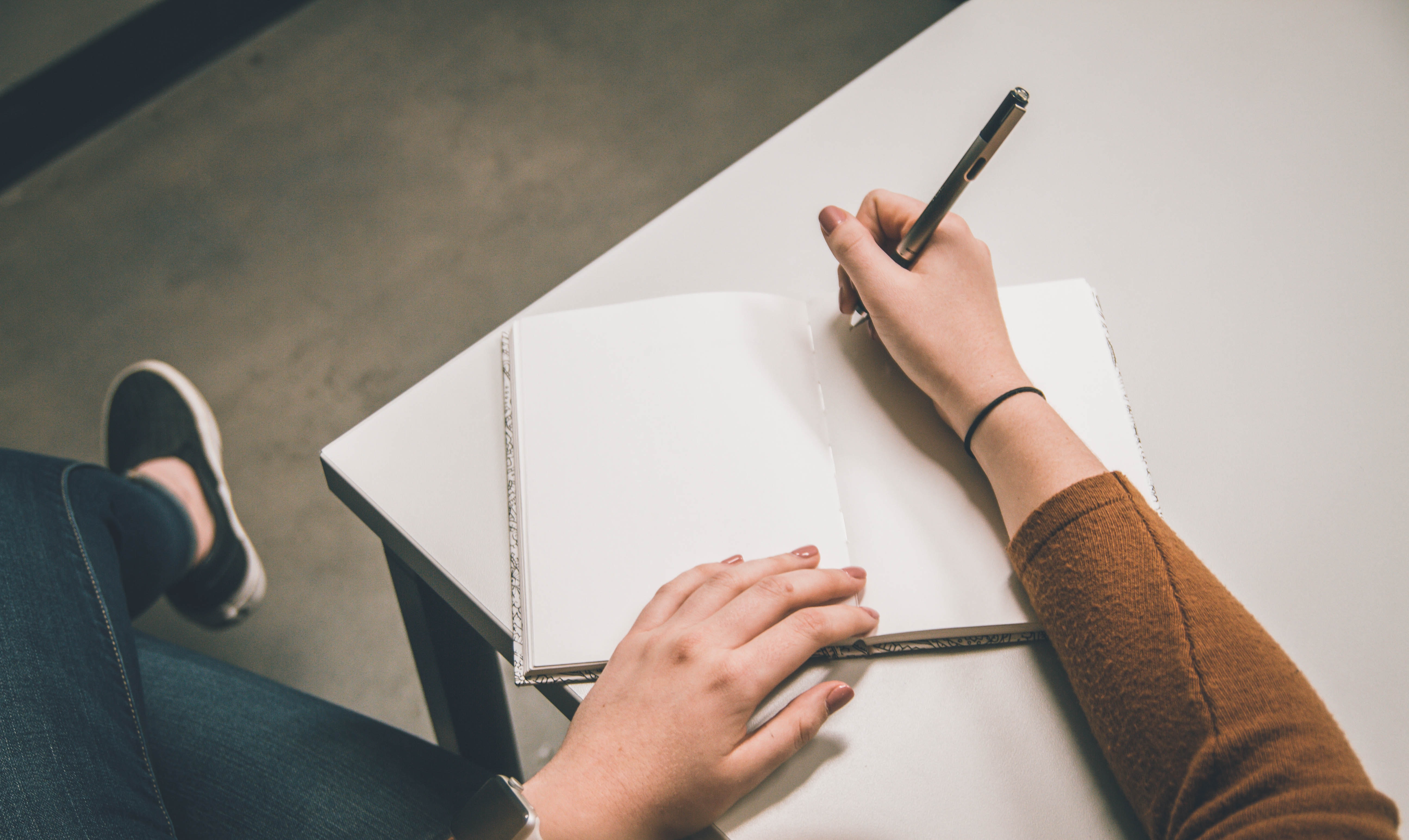 A photo of a person writing in a book - Unsplash.